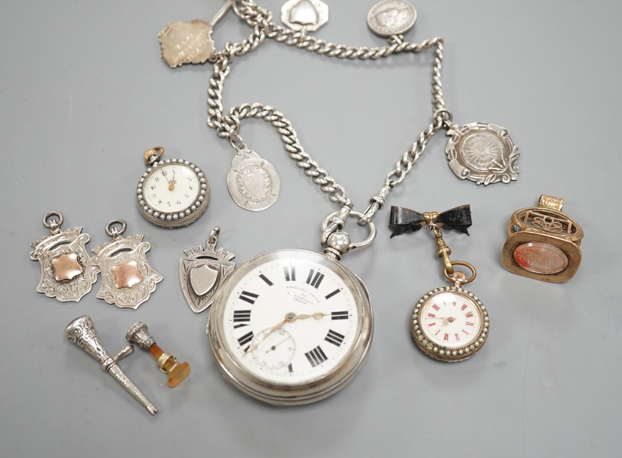 A George V silver open faced lever pocket watch, by A. Yewdall, Leeds, on a silver albert hung with silver medallions, two Swiss white metal and enamel fob watches, gilt fob seal, etc.
